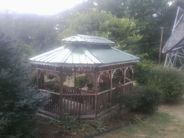 Green metal roof on a backyard gazebo surrounded by garden beds in Lakeville